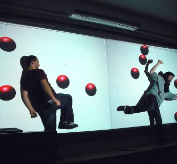 Interaktywna ściana reguje na ruchy stojących przy niej ludzi. Można więc podbijać wyświetlane na niej piłki.