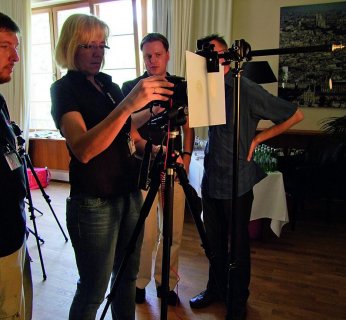 Uczestnicy warsztatów podczas fotografowania podświetlonego plasterka owocu.