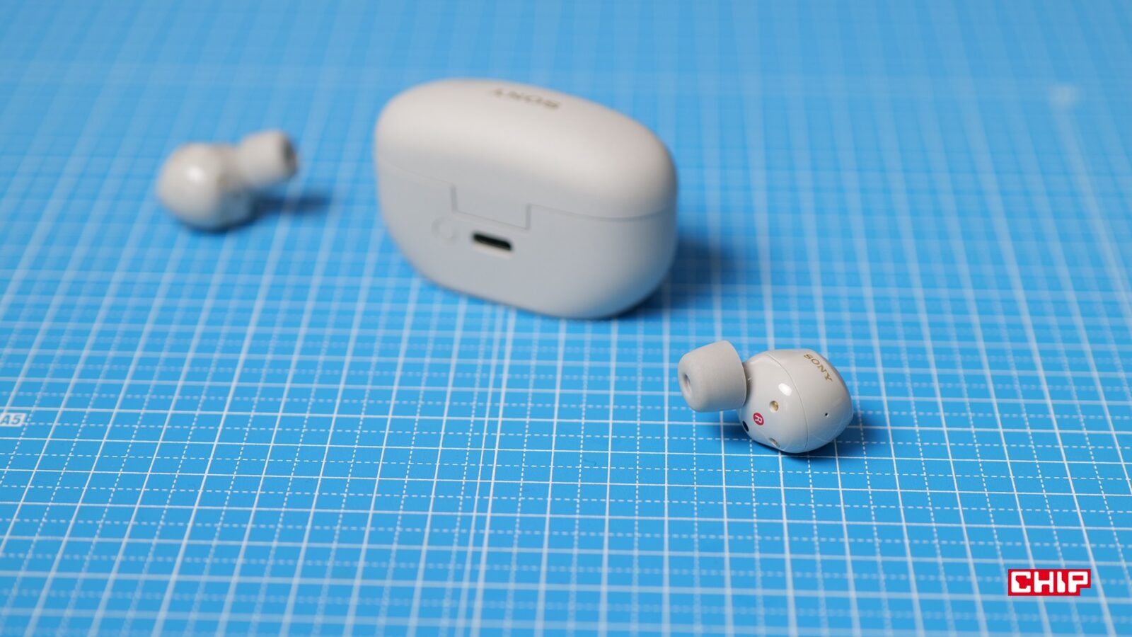 Zdjęcie prawej słuchawki Sony WF-1000XM5, w tle reszta zestawu